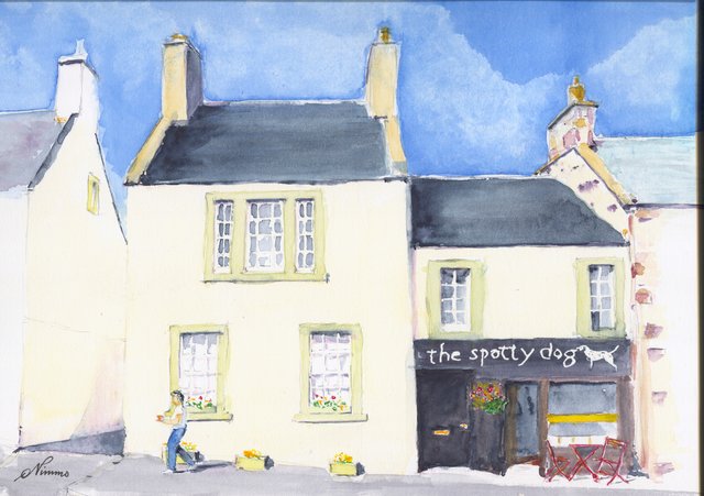 The Spotty Dog shop in Lauder, with a dalmatian on its dark fascia, beside a cream house, with a passer-by, planters and red café chairs.