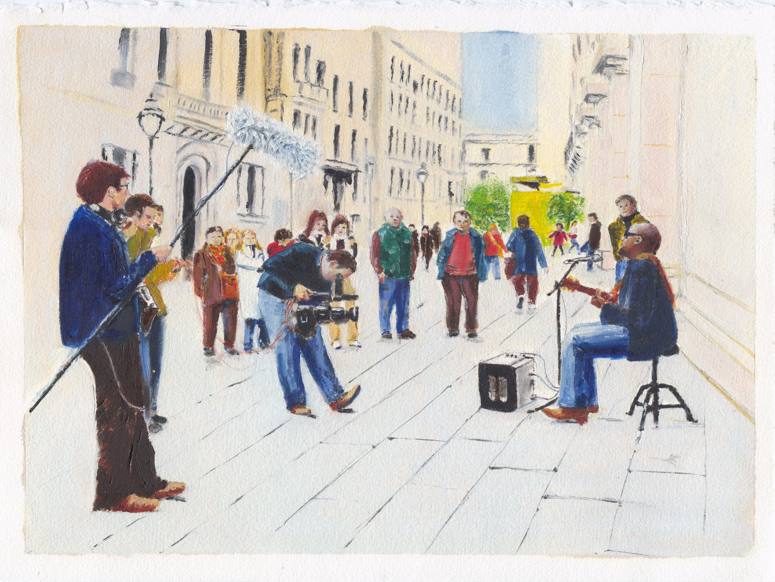 A street busker plays guitar on a stool beside his amplifier while a film crew with a boom microphone records him, passers-by watching on a sunlit paved street in Barcelona.